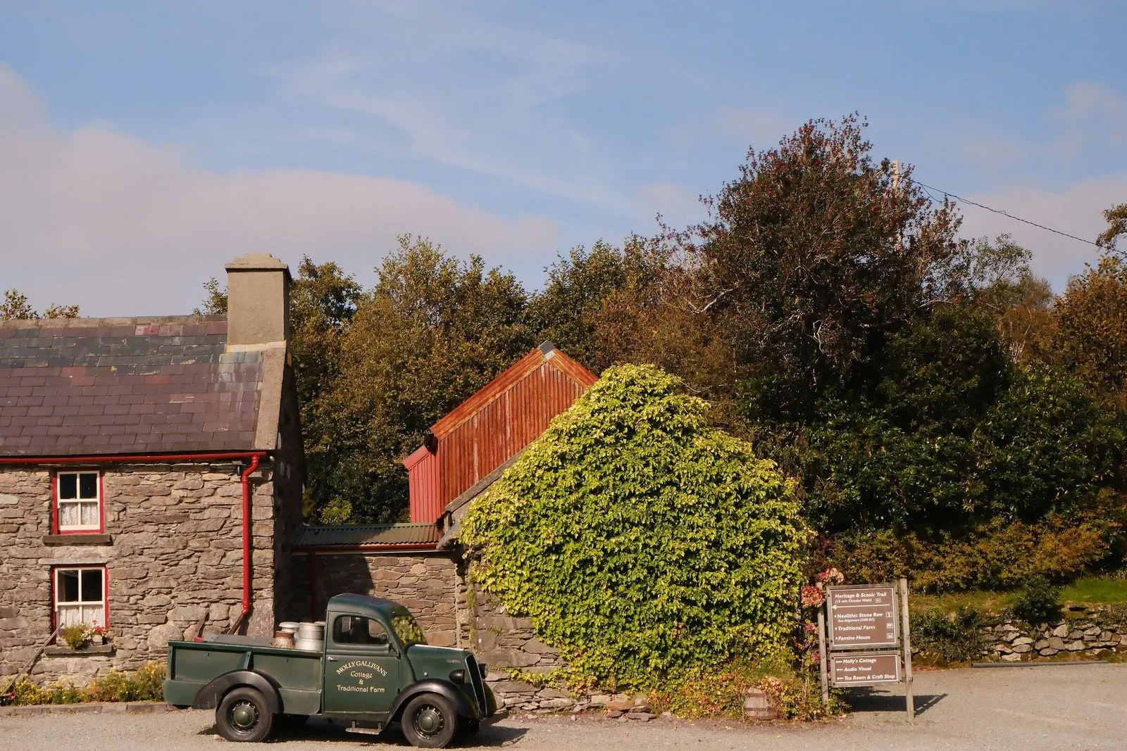 A stone farmhouse with a vintage green pickup truck parked outside, County Cork.