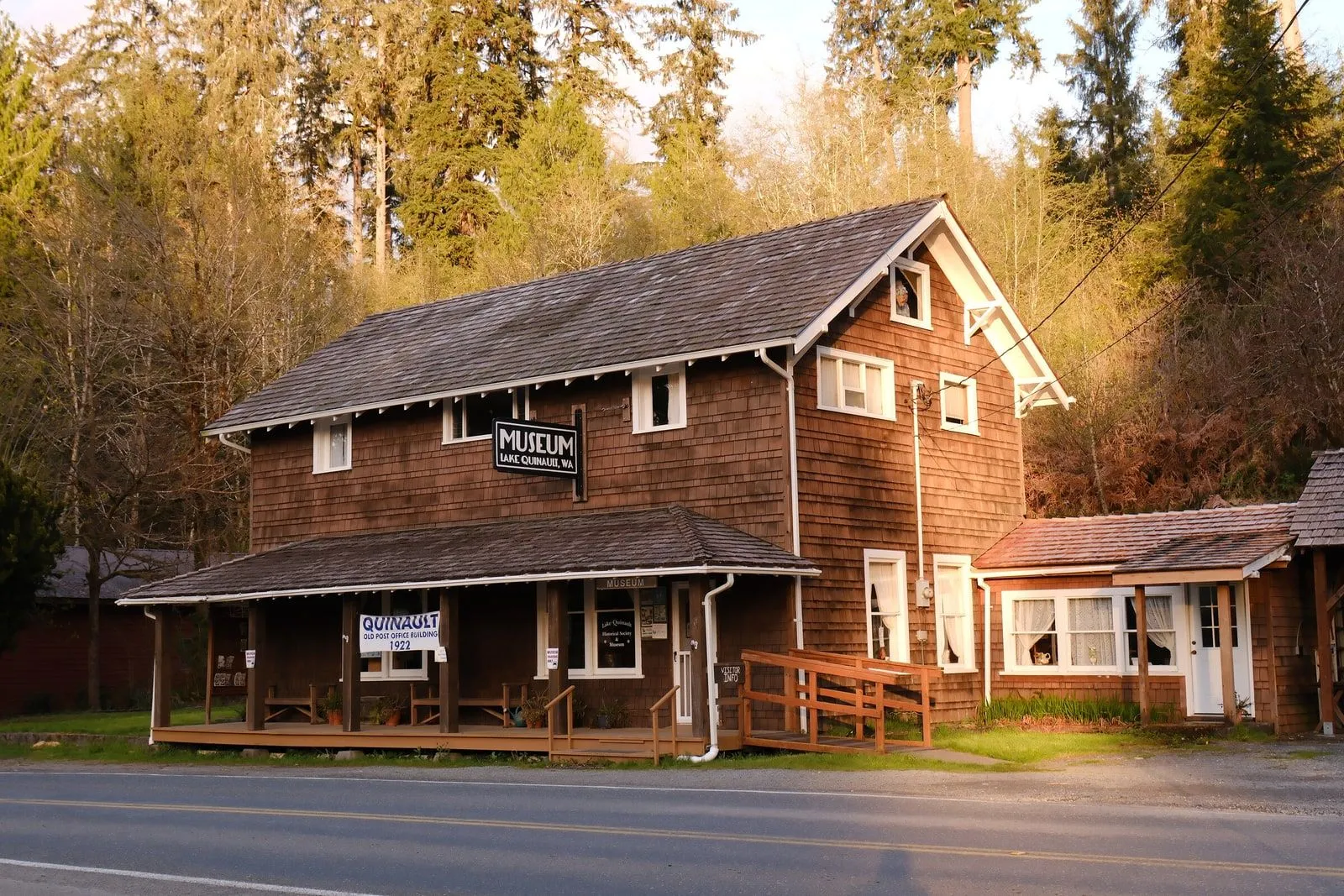 A small wooden trailhead building at the edge of dense forest.