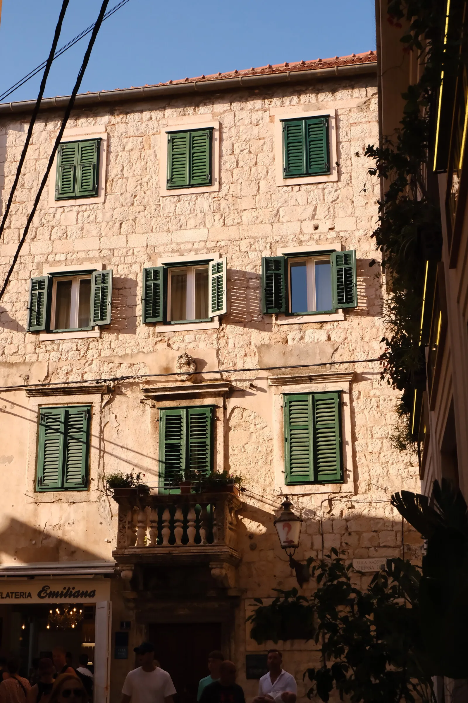 A pale stone facade with green-shuttered windows in Split old town.